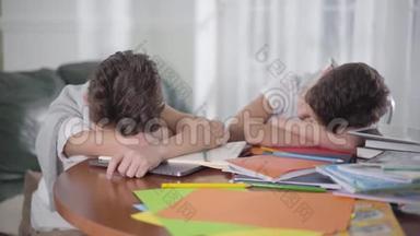 两个白人黑发<strong>男生</strong>睡在桌子上。 <strong>聪明的</strong>朋友或兄弟在书上睡着后